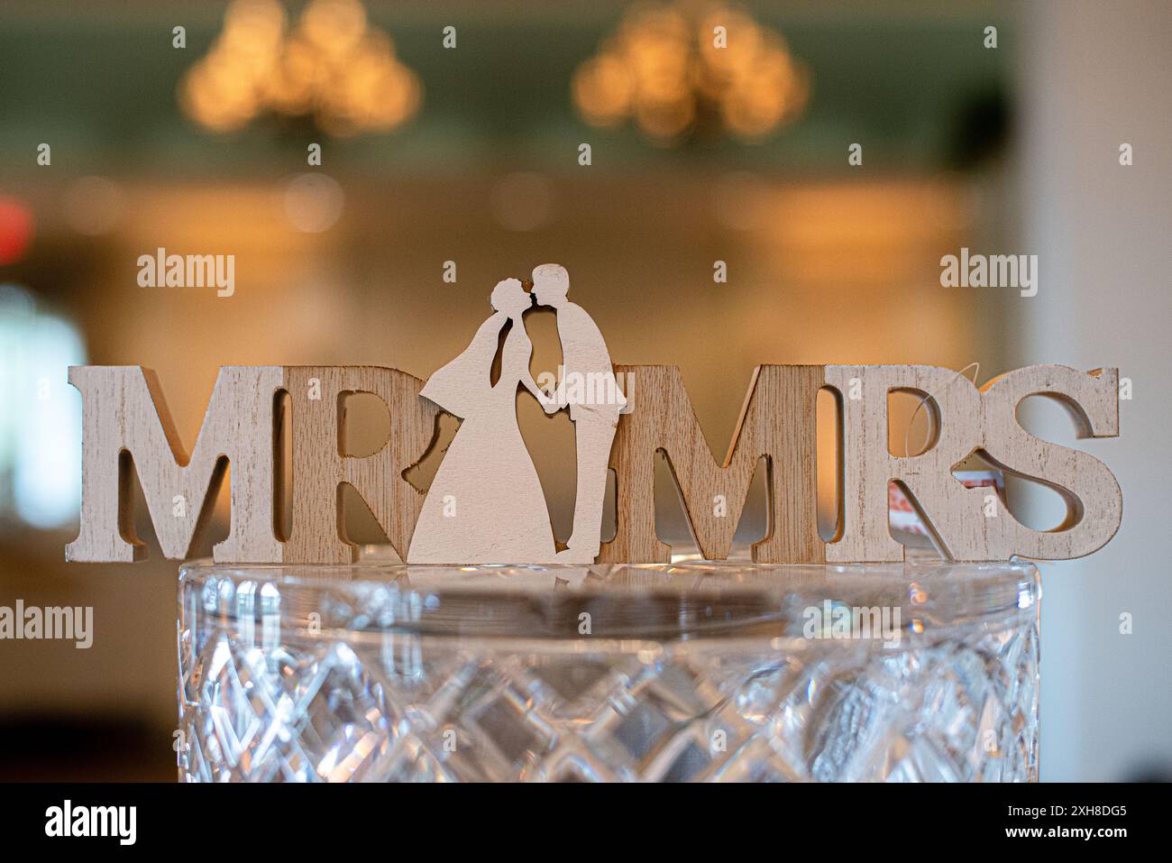 Entzückender Holzkuchenaufsatz in Form der Worte Mr und Mrs mit hölzernen Paaren, die sich in der Mitte küssen Stockfoto