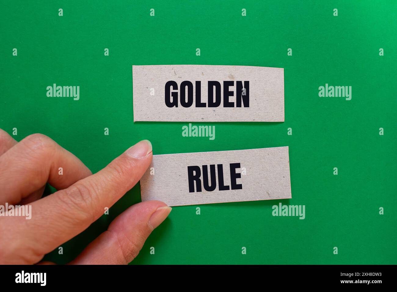 Goldene Regelbotschaft auf Papierstücken mit grünem Hintergrund. Konzeptionelles goldenes Regelsymbol. Kopierbereich. Stockfoto