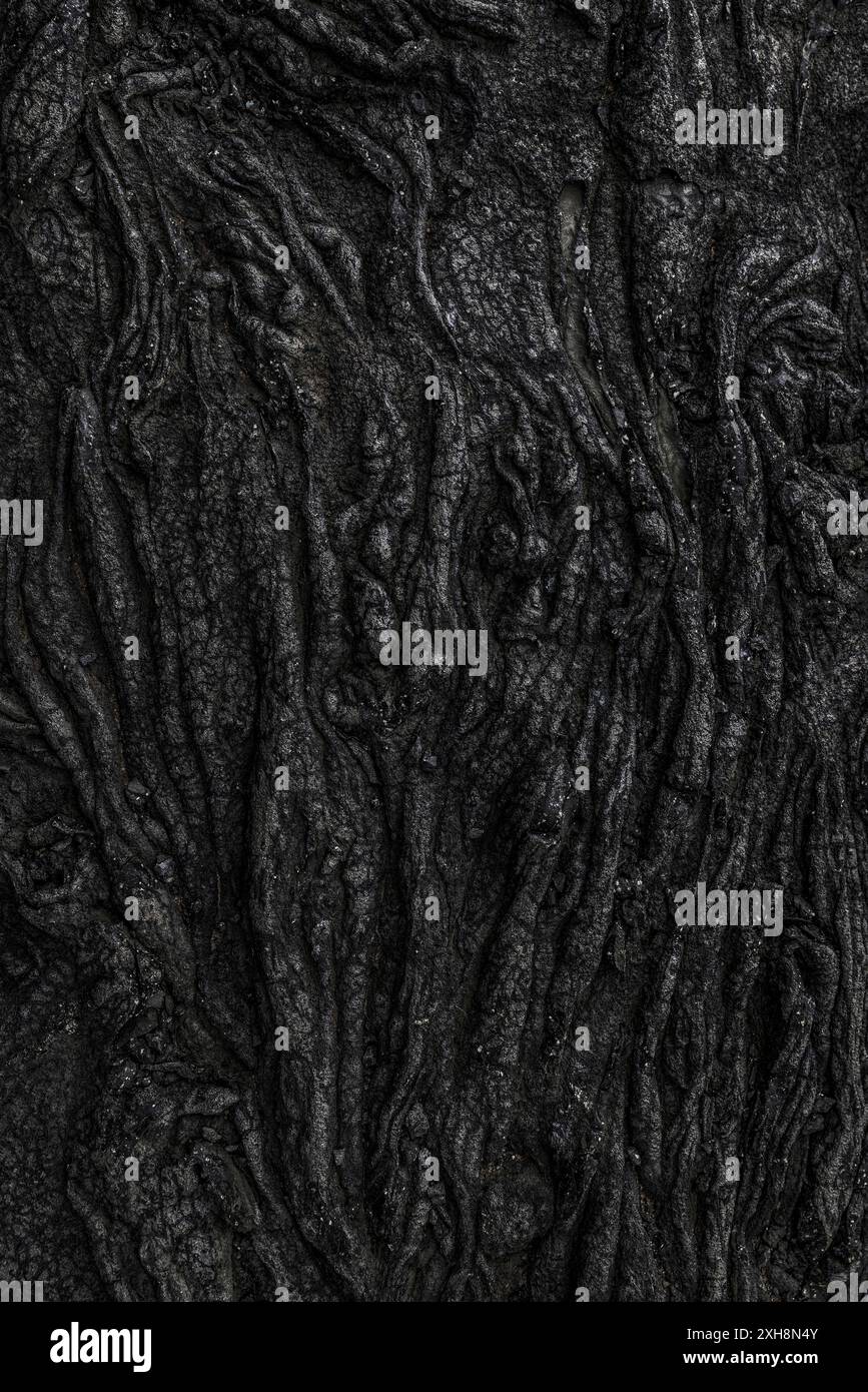 Erstarrter isländischer Lavastrom, der einen dunklen, strukturierten Hintergrund bildet Stockfoto