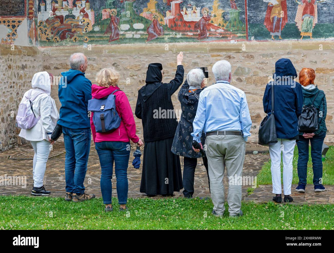 Nonne erklärt Touristen das Fresko an den Außenmauern der orthodoxen Kirche des Klosters Sucevita in der Region Bukowina, Rumänien Stockfoto