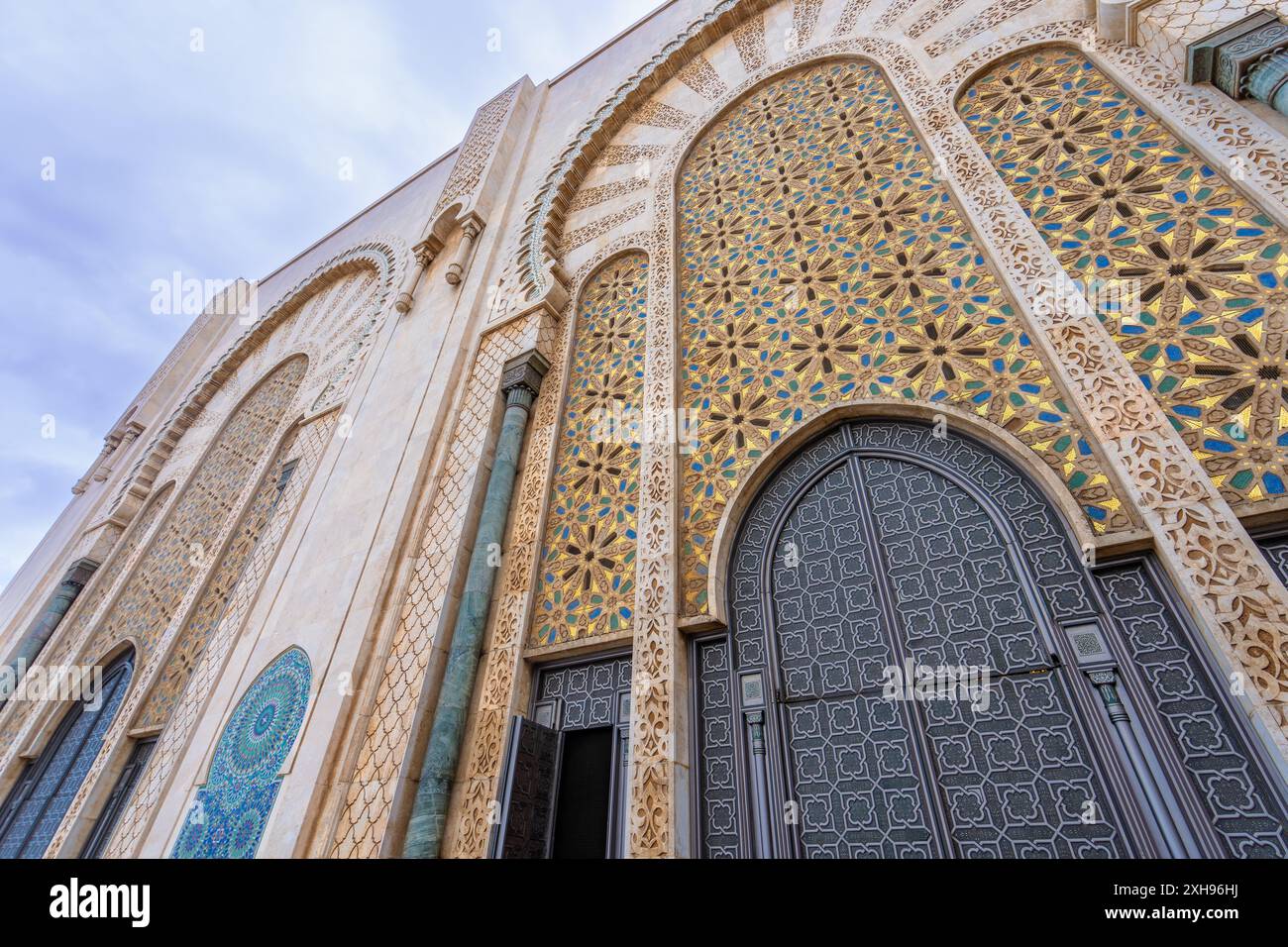 Die verzierten Türen an der Fassade der Hassan II Moschee zeigen komplexe geometrische Muster und Arabesken in Blau-, Gold- und Weißtönen. Casablan Stockfoto