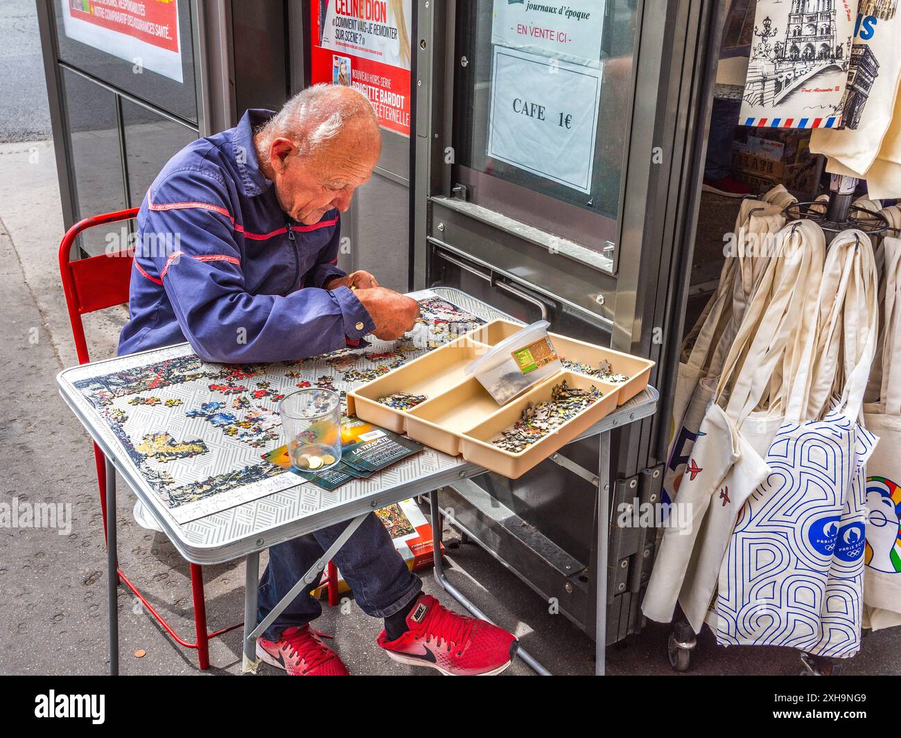 Mann der Straße (Obdachloser / Spendensammler), der ein Puzzle zusammenstellt - Paris 75006, Frankreich. Stockfoto