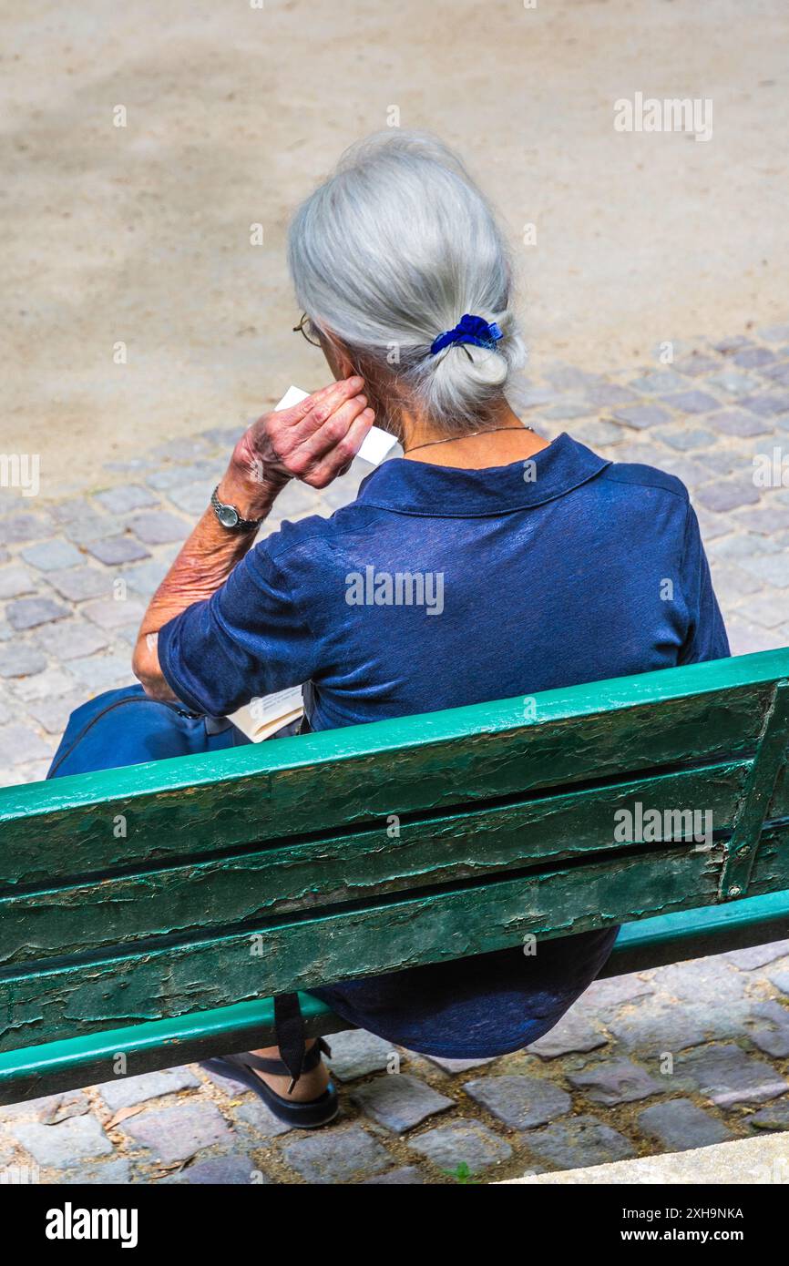 Reife Frau saß auf der Parkbank und las auf dem Square Boucicaut, Paris 75007, Frankreich. Stockfoto