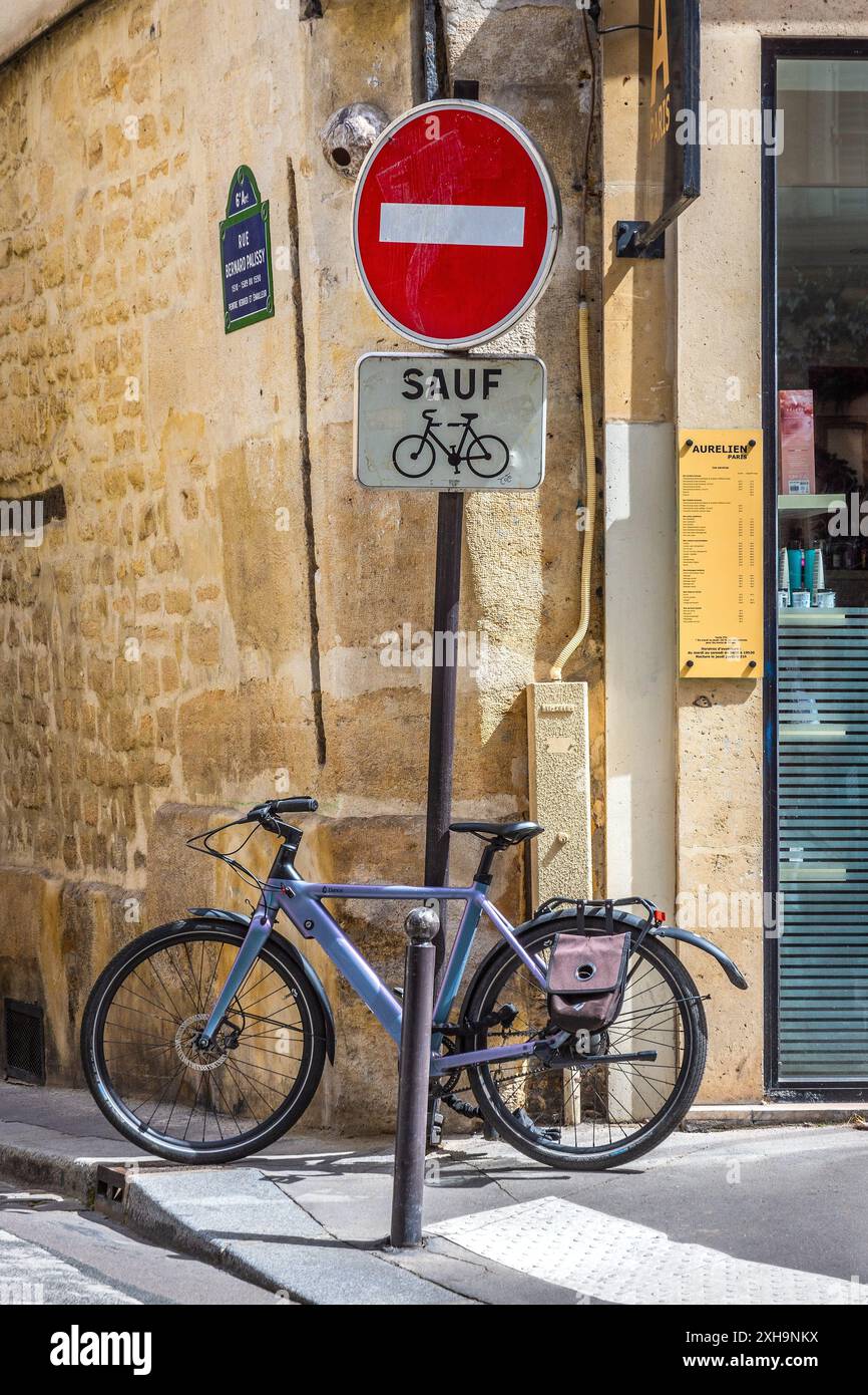 Ein eingeschlossenes, monatlich gemietetes elektrisches Dance-Fahrrad neben einem Straßenschild, das keinen Zutritt bietet, an der Rue du Dragon, Paris 75006, Frankreich. Stockfoto