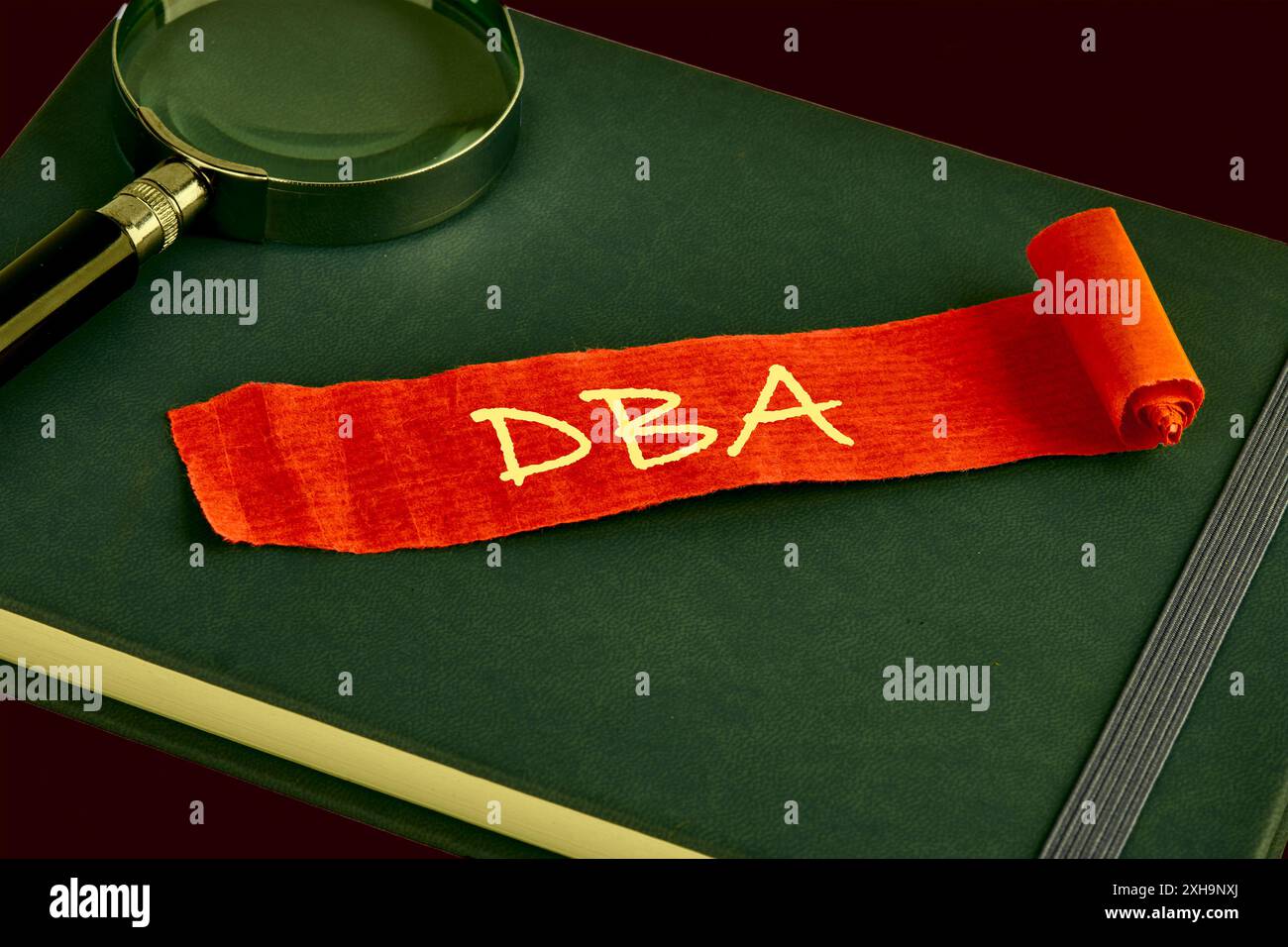 DBA-Briefe oder Doktor der Betriebswirtschaft auf einem roten Blatt Papier, das auf einem grünen Geschäftsbuch liegt Stockfoto