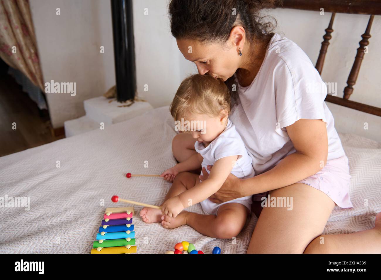 Eine Mutter genießt spielerische Momente mit ihrem Baby auf dem Bett und konzentriert sich dabei auf Familienbindung und frühkindliche Entwicklung. Das Bild fängt Liebe, Sorgfalt, an ein Stockfoto