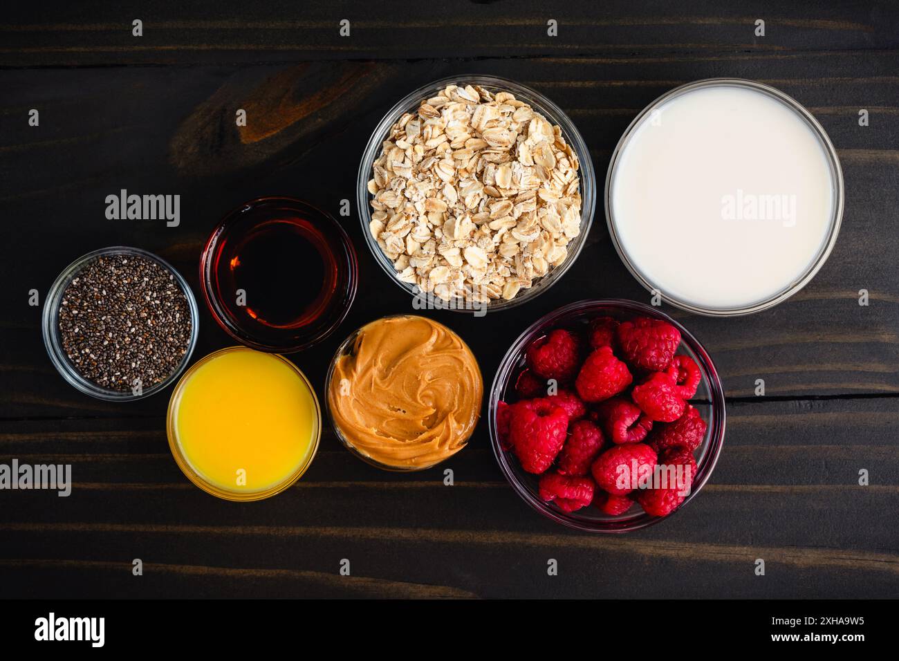 Himbeere Erdnussbutter Hafer Parfait Zutaten: Gesunde Frühstücksparfaits mit Himbeeren, gerollten Ocken, Früchten und Chiasamen in Glasbechern Stockfoto
