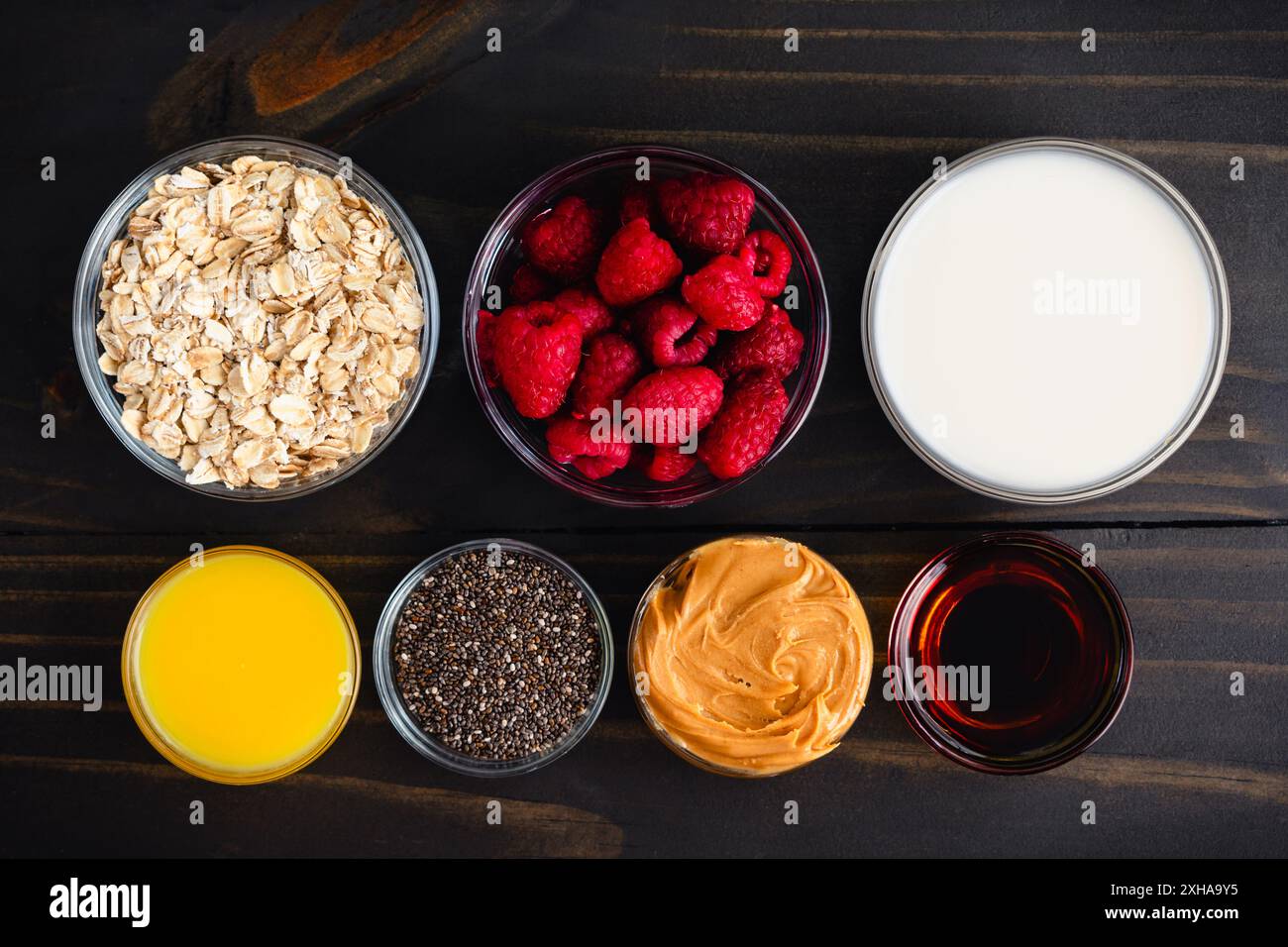 Himbeere Erdnussbutter Hafer Parfait Zutaten: Gesunde Frühstücksparfaits mit Himbeeren, gerollten Ocken, Früchten und Chiasamen in Glasbechern Stockfoto