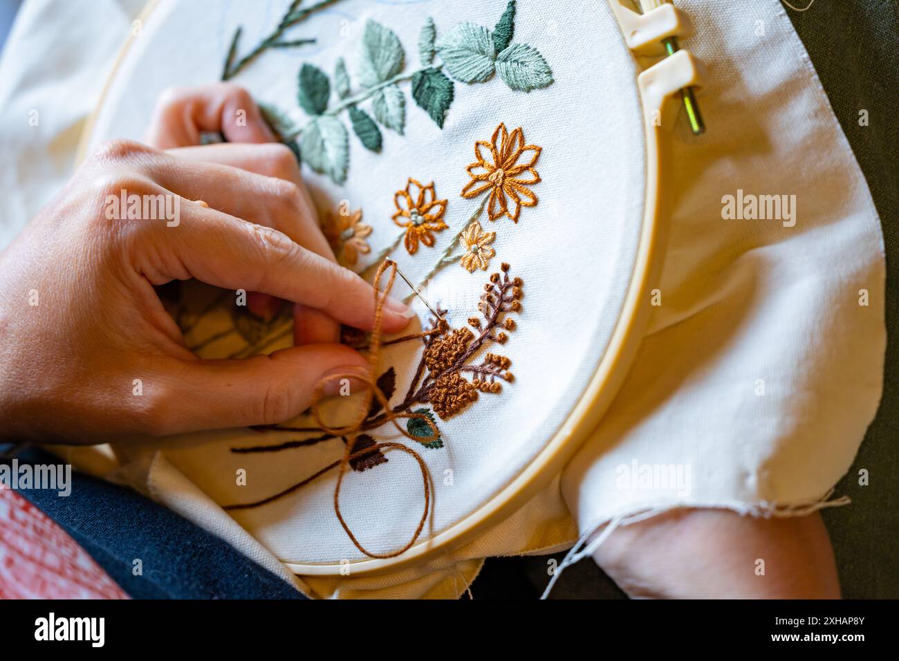 Frauenhände arbeiten an Stickerei mit Garn und Nadel Stockfoto