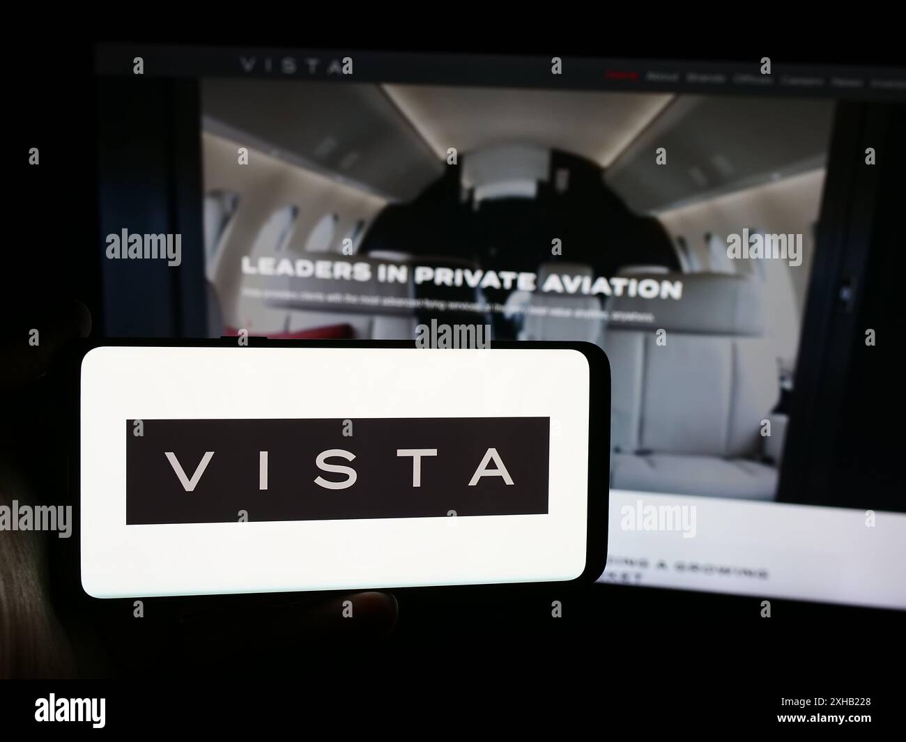 Person, die ein Smartphone mit dem Logo der Emirati Aviation Company Vista Global Holding Limited vor der Website hält. Schwerpunkt auf dem Display des Telefons. Stockfoto
