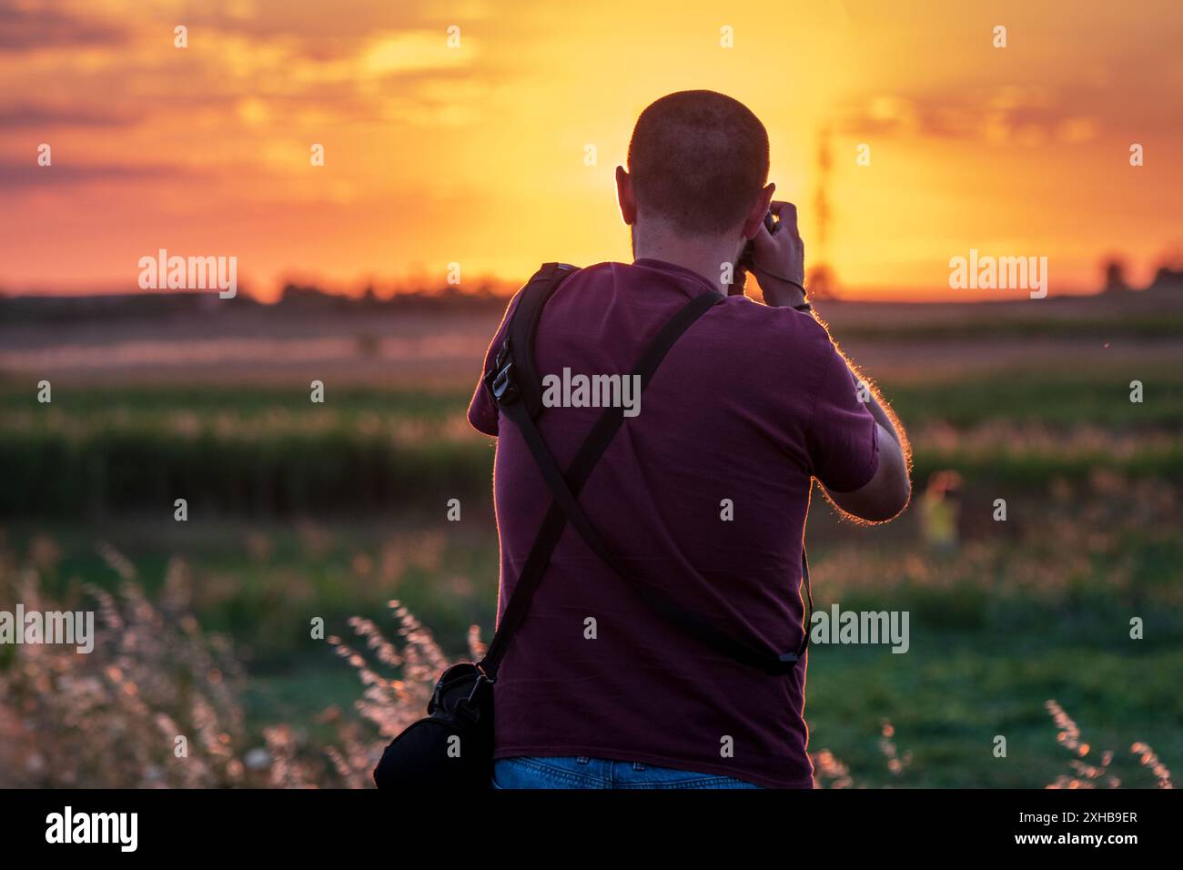 Fänger der Sonne. Fotograf, der den Sonnenuntergang einfängt, von hinten aufgenommen. Stockfoto