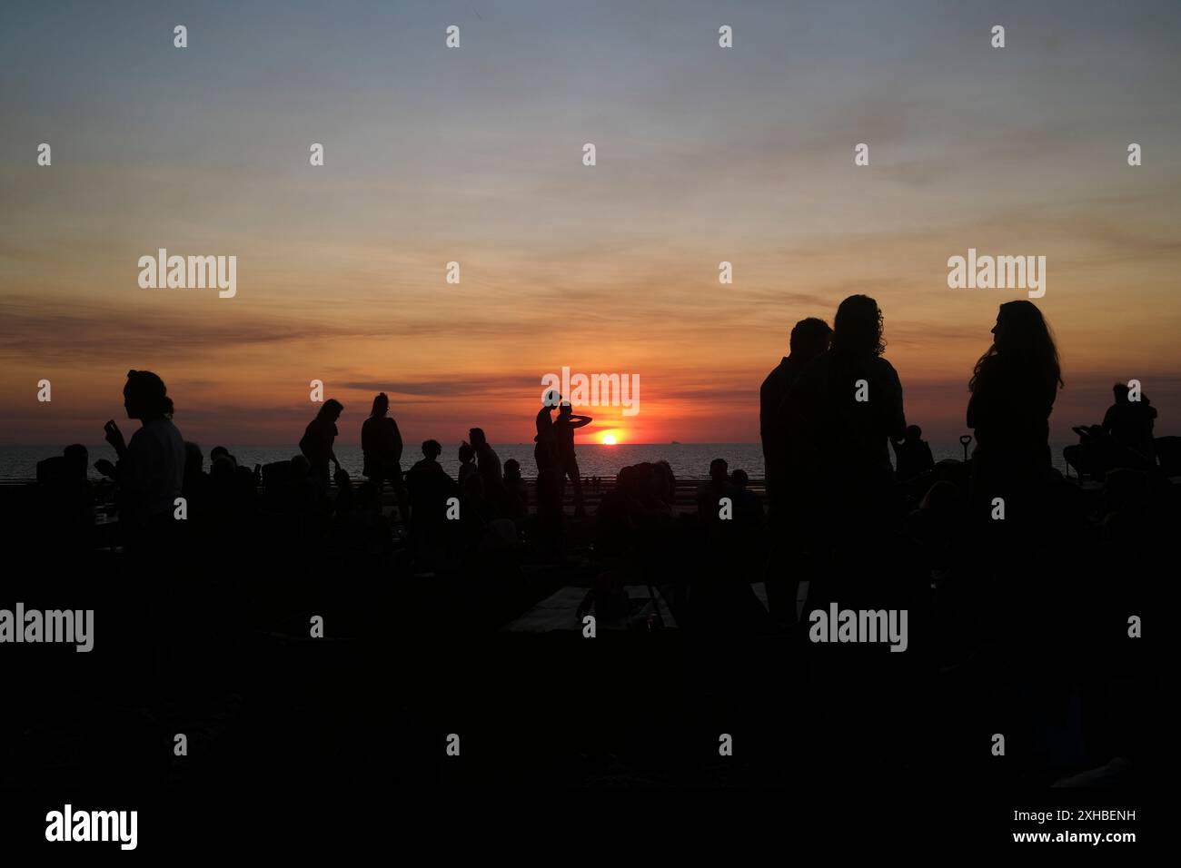 Silhouetten von Leuten, die eine Strandparty bei Sonnenuntergang genießen Stockfoto