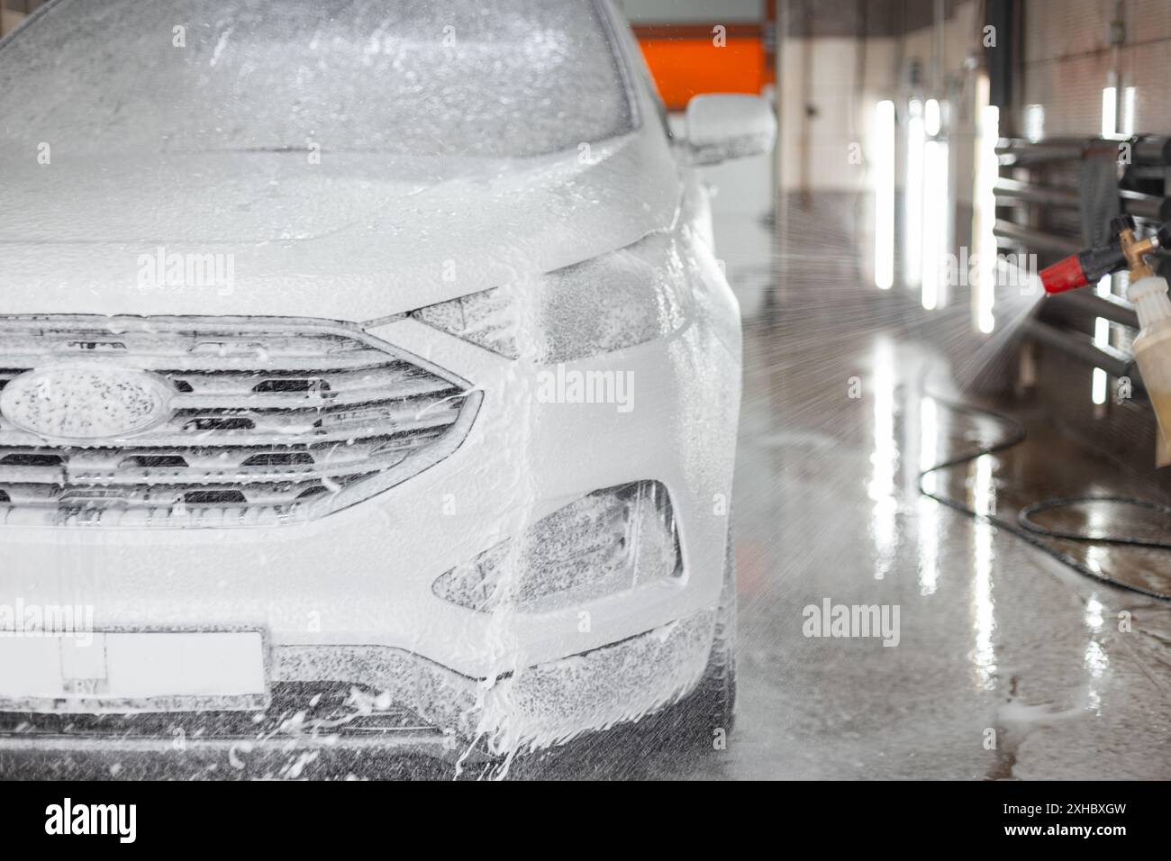 Das Auto mit Schaum wird in einer Autowaschanlage gewaschen. Autopflege und -Reinigung Stockfoto