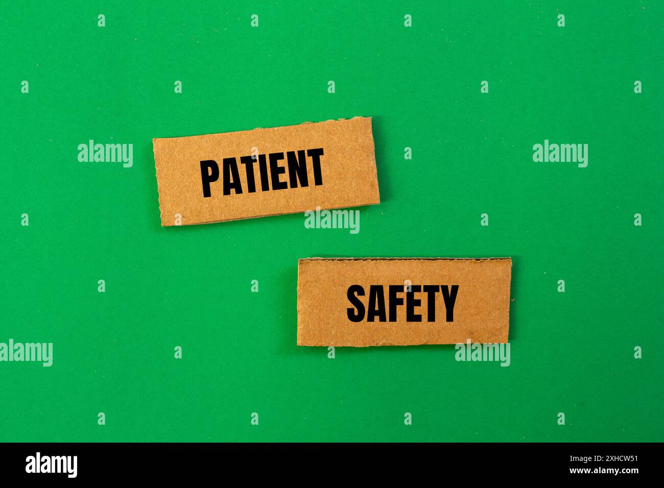 Patientensicherheitsschild auf gerissenen Papppapierstücken mit grünem Hintergrund. Konzeptionelles Patientensicherheitssymbol. Kopierbereich. Stockfoto
