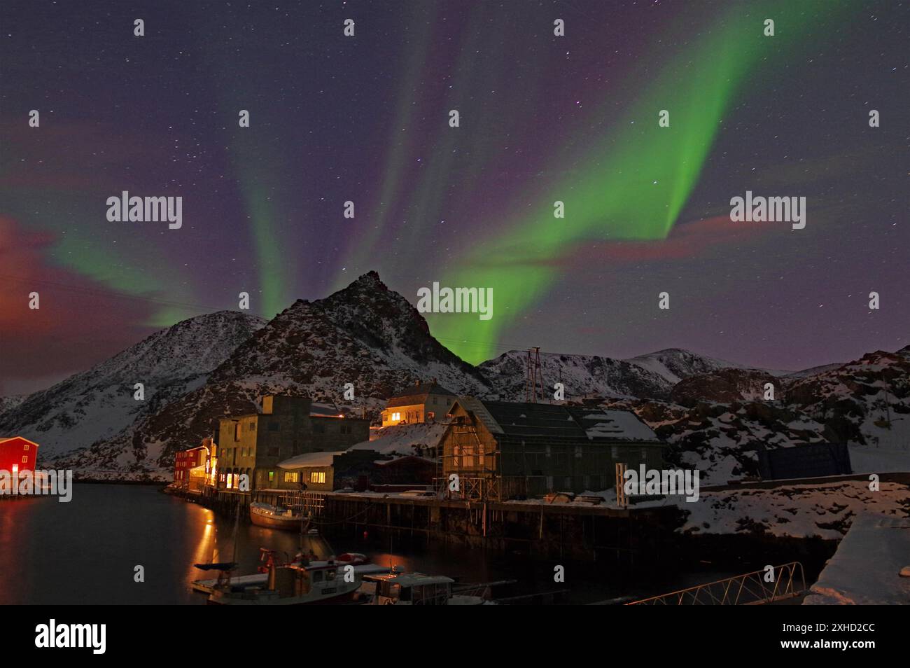 Nachtszene mit Nordlichtern am Himmel, schneebedeckte Berge und Häuser am Wasser, Winter, Nyksund, Langoya, Vesteralen, Nordland, Norwegen Stockfoto