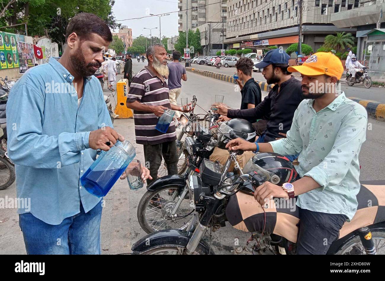 Devotee verteilt Trinkwasser unter Menschen in einem „Sabeel“, das von der Pakistan Association of Press Photographs (PAPP) während des Heiligen Monats Muharram-ul-Haram organisiert wurde, außerhalb des Karachi Presseclubs am Samstag, den 13. Juli 2024. Stockfoto