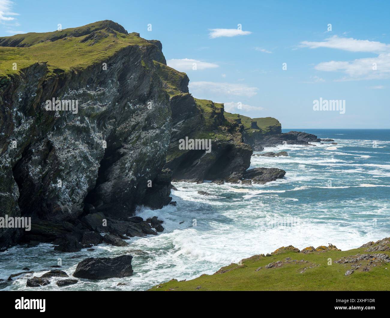 Seevögelklippen bedeckt mit Guano von nistenden Seevögeln mit Wellen und Surfen unten in Pig's Paradise, June, Isle of Colonsay, Schottland, Großbritannien Stockfoto