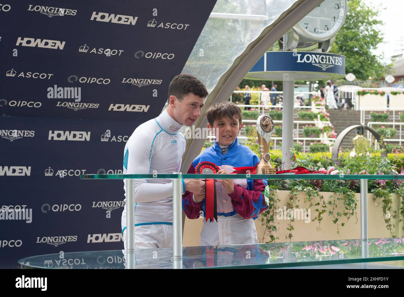 Ascot, Berkshire, Großbritannien. Juli 2024. Jockey Oisin Murphy präsentiert Reiter Henry Graham eine Rosette, nachdem er beim „Dragon TV and Film Studios Pony Race 138cm & Under“ auf der Ascot Racecourse in Berkshire beim Summer Mile Family Raceday auf dem Pony Laybalands Captain Scarlet gefahren ist. Quelle: Maureen McLean/Alamy Live News Stockfoto