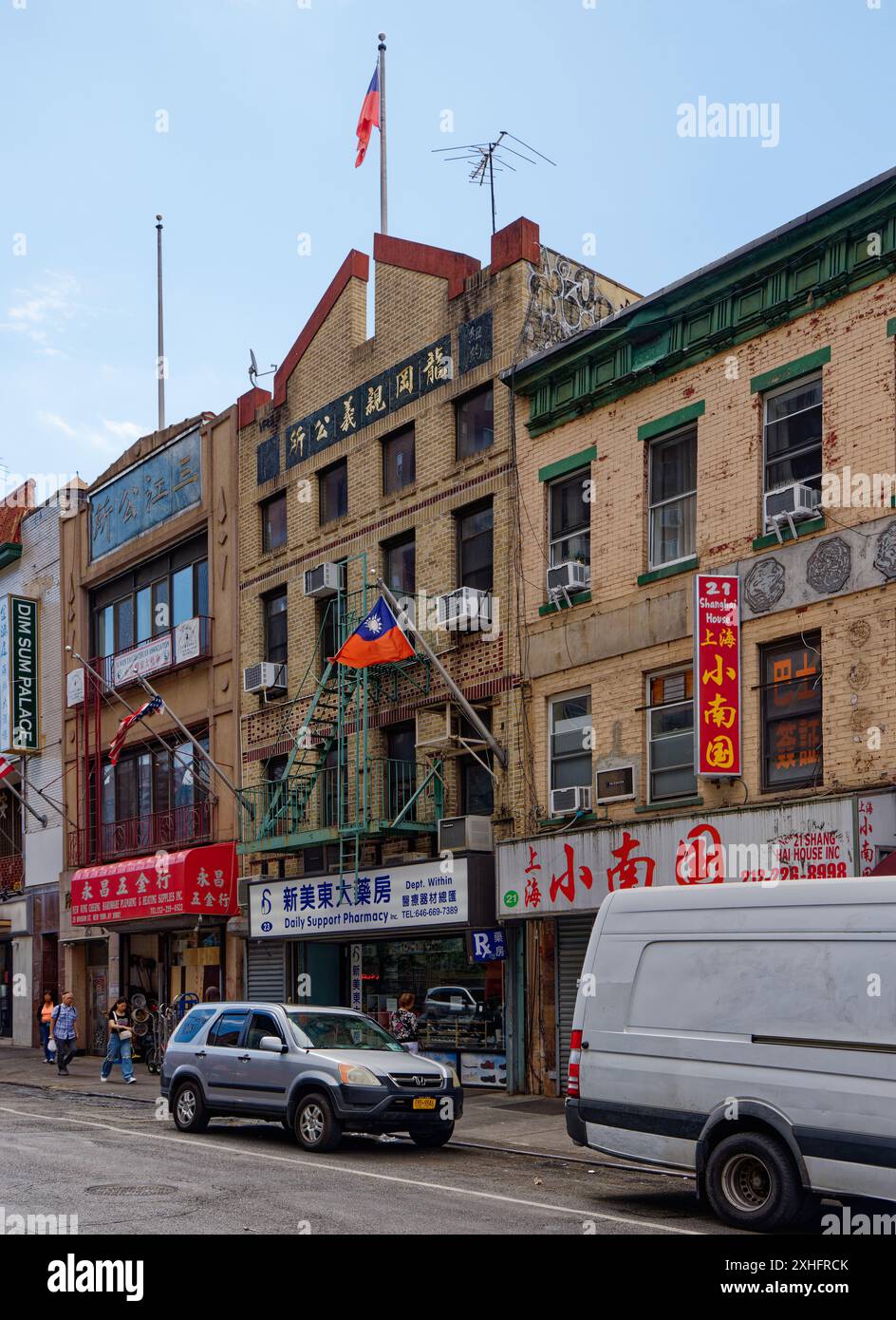 NYC Chinatown: US-amerikanische und taiwanesische Flaggen fliegen über der chinesischen Apotheke in der 23 Division Street, einem vierstöckigen Geschäftsgebäude aus polychromem Backstein. Stockfoto