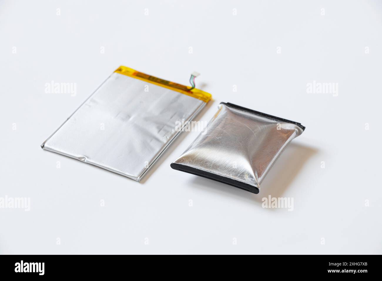 Eine durch Überhitzung geschwollene Telefonbatterie liegt auf einem weißen Hintergrund, die Telefonbatterie ist aufgeblasen Stockfoto