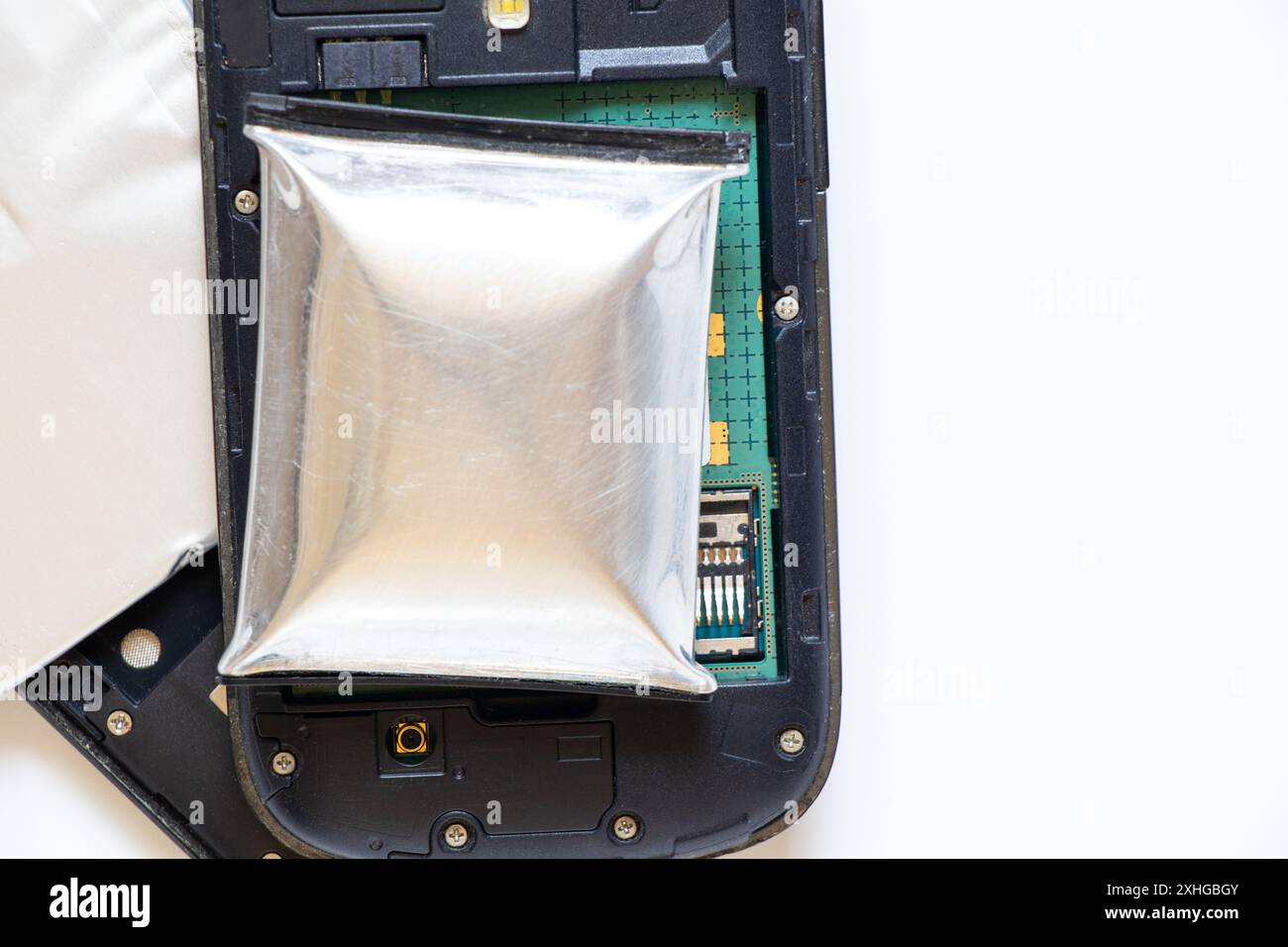 Ein Telefonakku ist durch Überhitzung geschwollen und ein zerlegtes Telefon liegt auf einem weißen Hintergrund, der Telefonakku ist aufgeblasen, Telefonreparatur Stockfoto