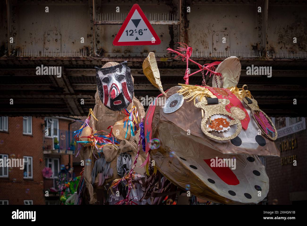 Folkestone, Kent, Großbritannien. Juli 2024. Charivari Day Jährliche Parade. Britische Folklore und rituelle Traditionen sind das Thema der markanten Karnevalsparade in diesem Jahr. Massive Kopfskulpturen schmücken die Schultern der lokalen Jugendlichen mit Grundschulkindern im ganzen Viertel, die in den Farben des Jahres gekleidet sind. Der Charivari Day, der vom Stade über die Stadt bis zum Leas Bandstand marschiert, ist seit 1997 die größte Tradition Folkestones und zieht Hunderte von Zuschauern in die Hafenstadt am Meer an. Guy Corbishley/Alamy Live News Stockfoto