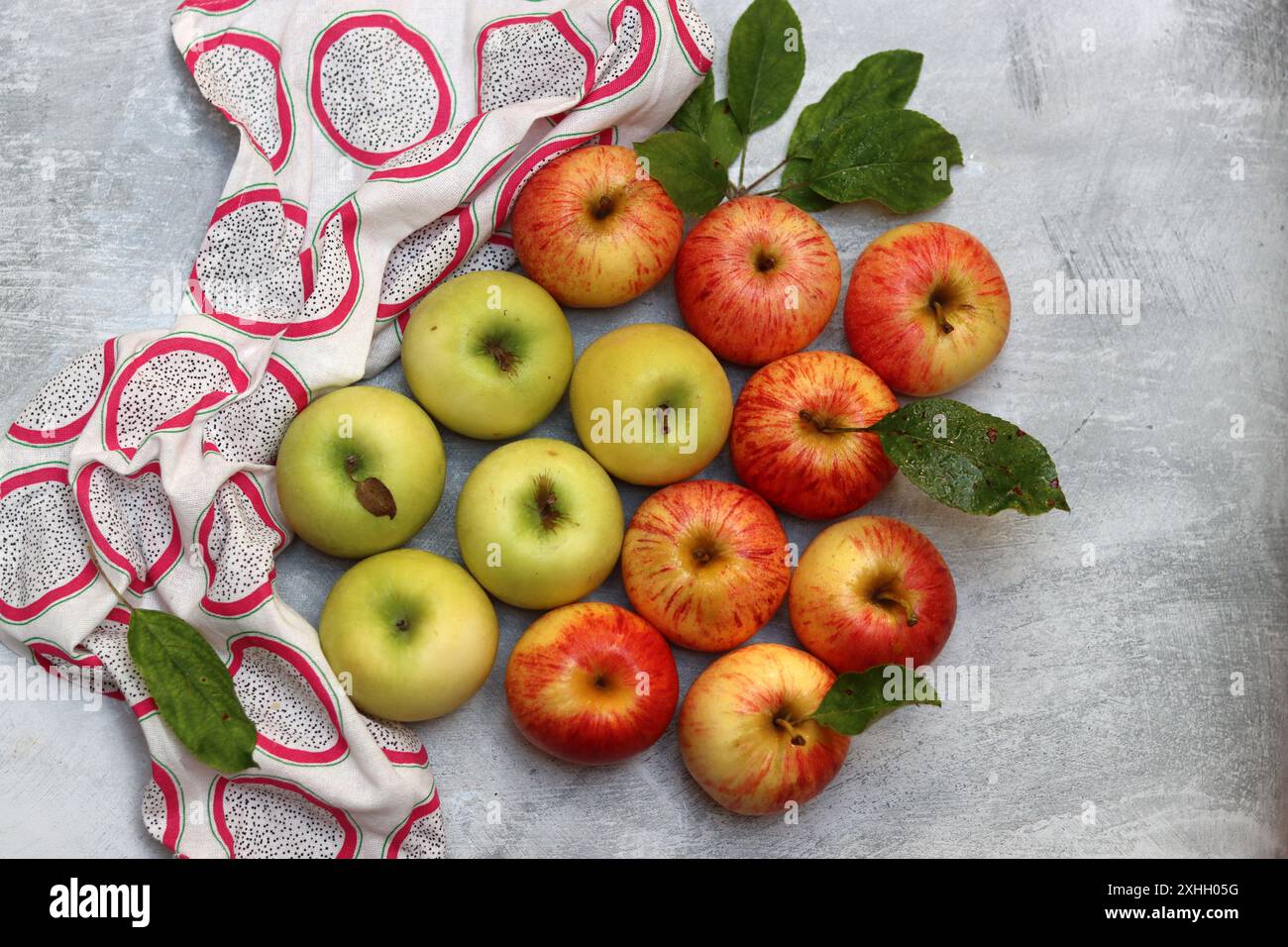 Wunderschöne grüne und rote Äpfel von oben. Saftige Bio-Früchte auf hellgrauem, strukturiertem Hintergrund mit Platz für Text. Konzept für gesunde Ernährung. Stockfoto