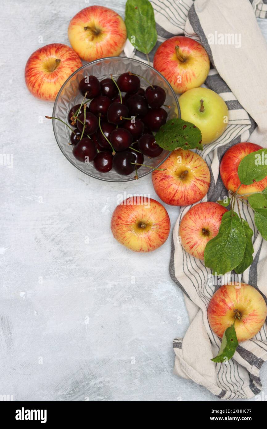 Rote Äpfel und Kirschen auf einem Teller auf hellem Hintergrund mit Kopierraum. Nahaufnahme der Sommerfrüchte. Fresh-Konzept. Reife rote Äpfel Stockfoto