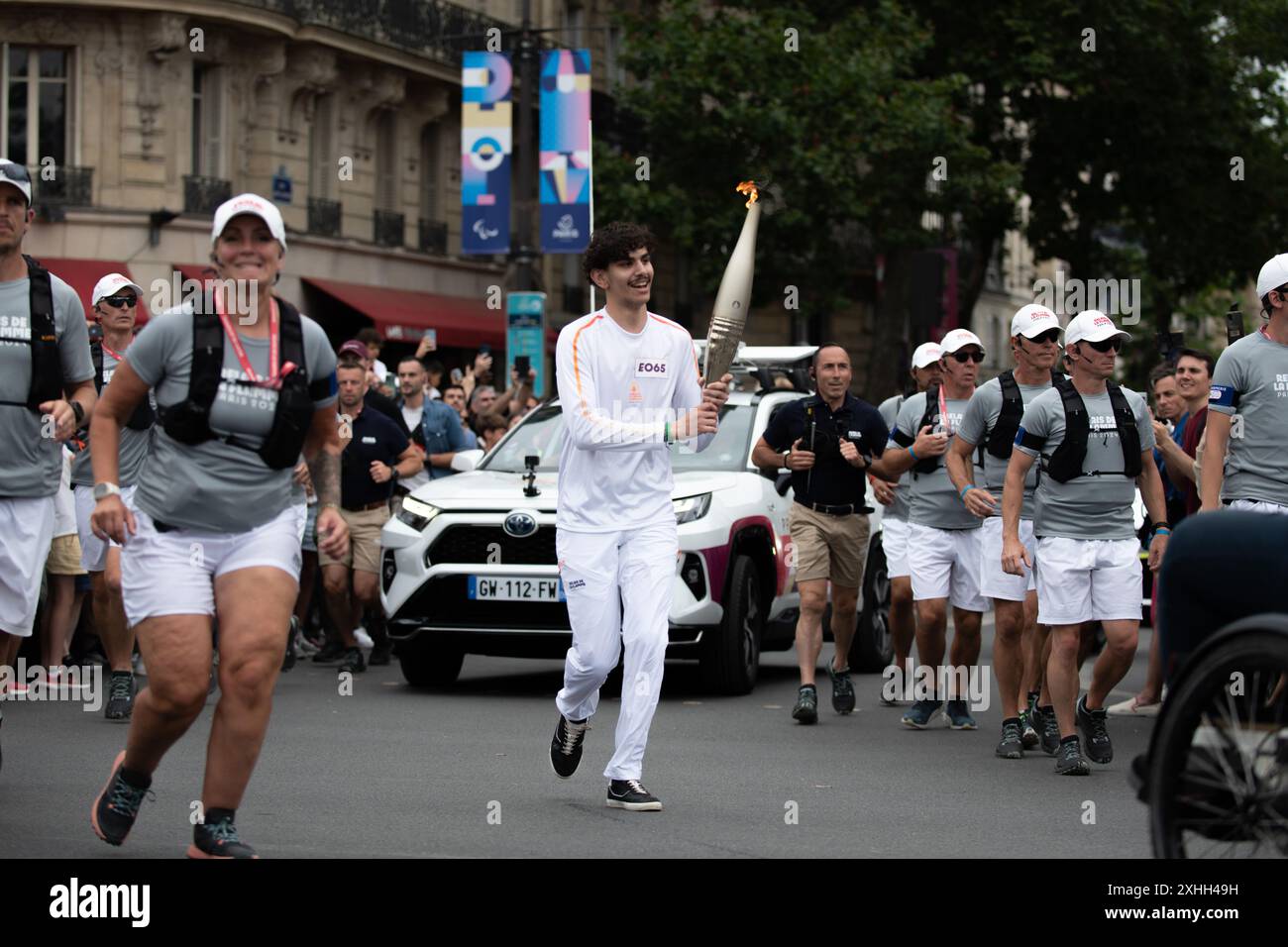 14. Juli 2024, Paris, Frankreich. Ein Fackelträger führt die olympische Fackel durch den Place de la Bastille, während sie durch Paris fährt. Quelle: Jay Kogler/Alamy Live News Stockfoto