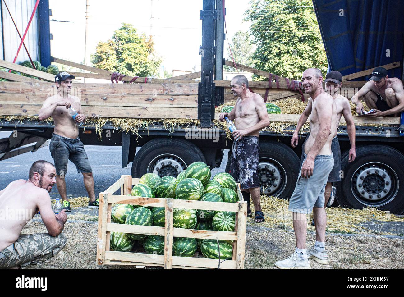 Wassermelonenbeweger in Kiew, Ukraine, machen eine Pause, um etwas Wasser in der Juli-Hitze zu trinken, da die Wirtschaft vom Krieg getroffen wird, viele suchen diesen schnellen Dollar/Hrywna Stockfoto
