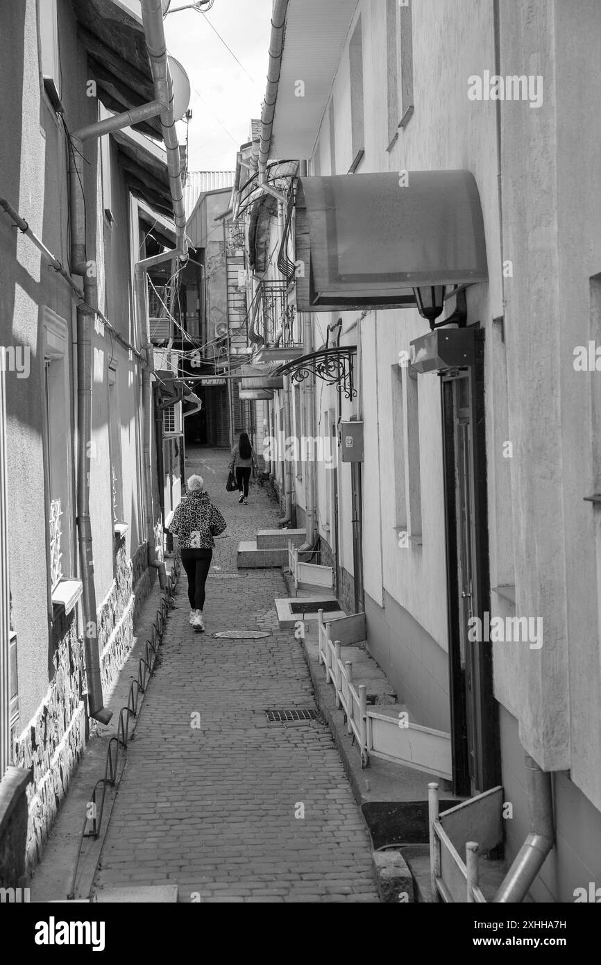 Uschhorod, Ukraine - 19. April 2024: Die Menschen laufen entlang der Wohnarchitektur auf engen Gassen in der Altstadt. Uschhorod ist eine Stadt und Gemeinde Stockfoto