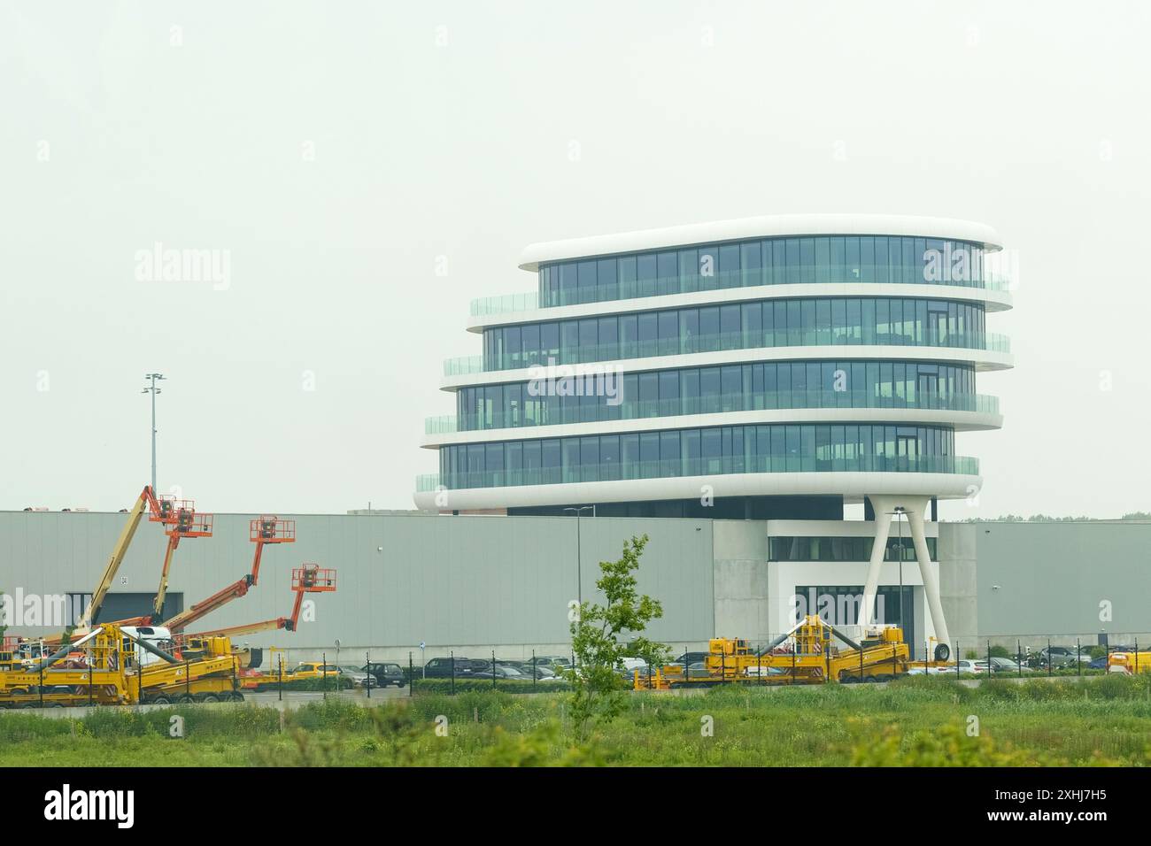 Antwerpen, Belgien - 22. Mai 2023: Ein modernes, weißes Bürogebäude mit großen Fenstern und geschwungenem Design ist mit gelben Luftschliften abgebildet Stockfoto