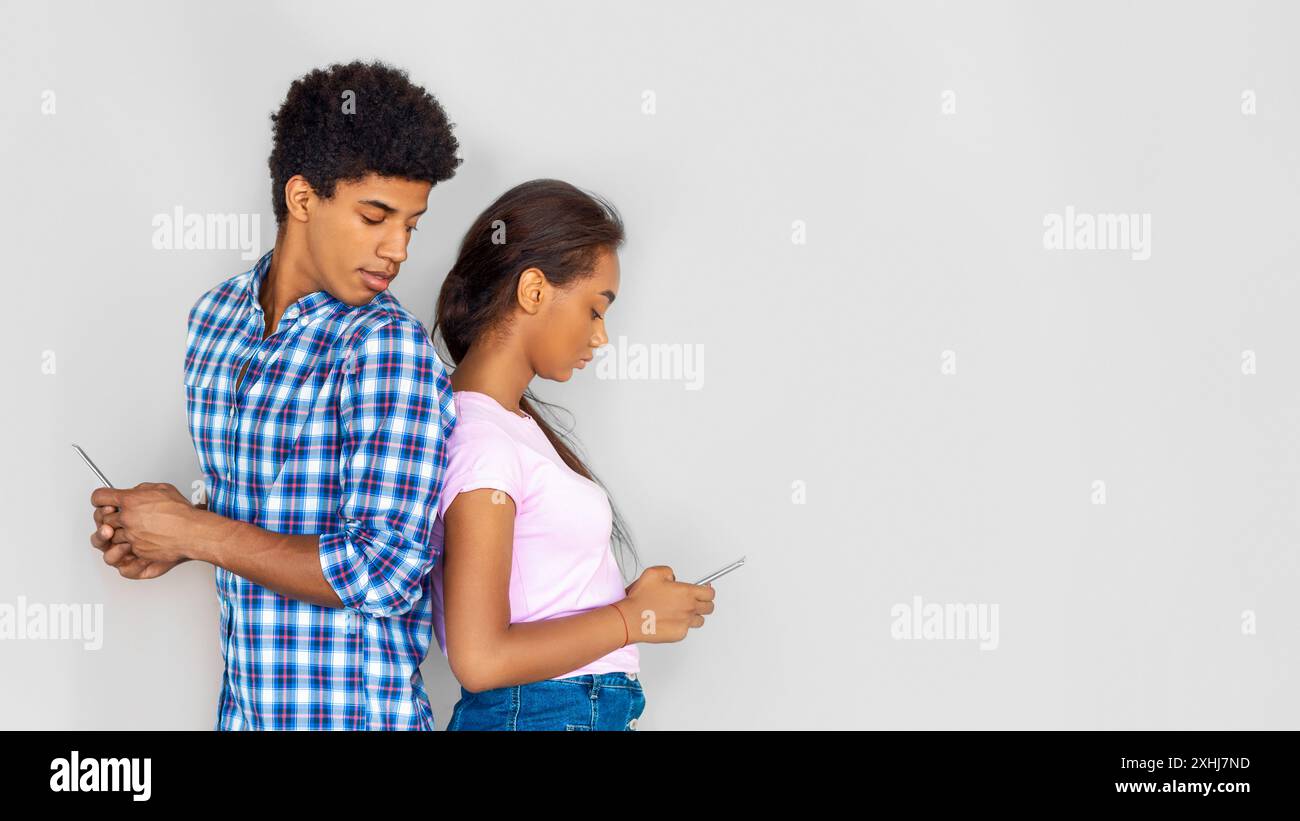 Teenager-Paar, Das Smartphones Gegen Die Weiße Wand Benutzt Stockfoto