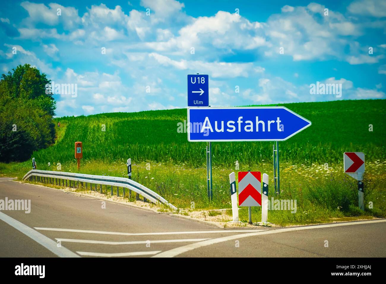 Ausfahrt, Autobahnausfahrt, Straßenschild, Verkehr, Verkehrsschild, Autobahn, Straße, Richtungsschild, Ausfahrtsschild, Ulm, U18, grüne Wiese, blauer Himmel, Straßenschäden, Bauarbeiten, Warnschild, Verkehrssicherheit, Wegweiser, Richtungsanzeiger, Verkehrsanweisung, Fahrtrichtung, Autobahnnetz, Navigation, Verkehrsweg. *** Ausfahrt, Autobahnausfahrt, Verkehrsschild, Verkehrszeichen, autobahn, Straße, Wegweiser, Ausfahrt, Ulm, U18, grüne Wiese, blauer Himmel, Straßenschäden, Bauarbeiten, Warnschild, Verkehrssicherheit, Wegweiser, Blinker, Verkehrshinweise, Fahrtrichtung, Autobahn n Stockfoto