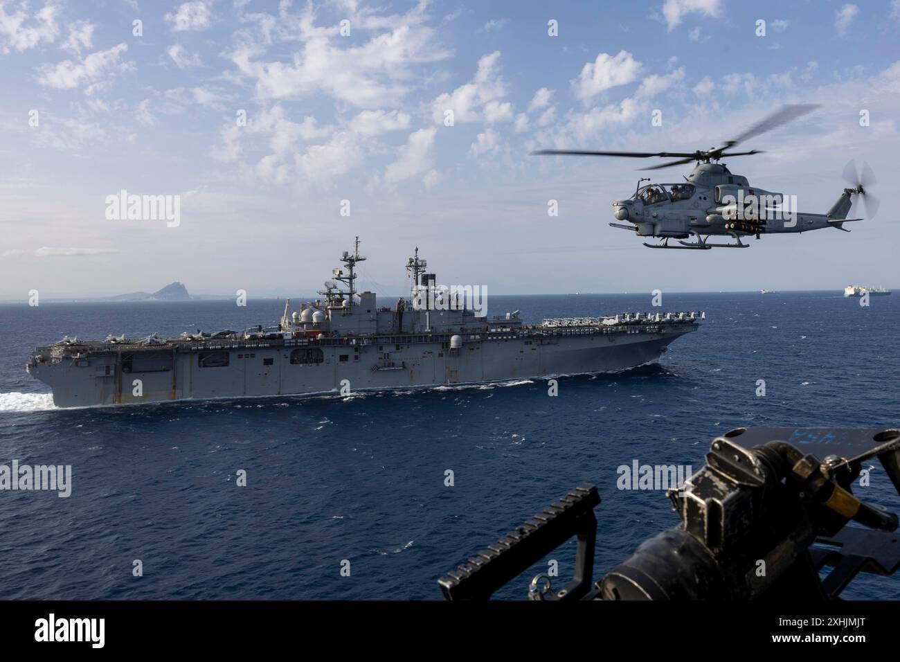 240626-N-XO158-1213 STRASSE VON GIBRALTAR (26. Juni 2024) eine AH-1Z Viper, die den „Blue Knights“ der Marine Medium Tiltrotor Squadron (VMM) 365 (verstärkt) zugeordnet ist, patrouilliert neben dem amphibischen Angriffsschiff USS Wasp (LHD 1), während das Schiff die Straße von Gibraltar durchquert, 26. Juni 2024. Wasp führt Operationen im US Naval Forces Europe Area als Flaggschiff der Wasp Amphibious Ready Group (WSP ARG)-24th Marine Expeditionary Unit (MEU) Special Operations Capable (SOC) durch. Die WSP ARG-24th MEU (SOC) unterstützt High-End-Kampfübungen und demonstriert Geschwindigkeit A Stockfoto