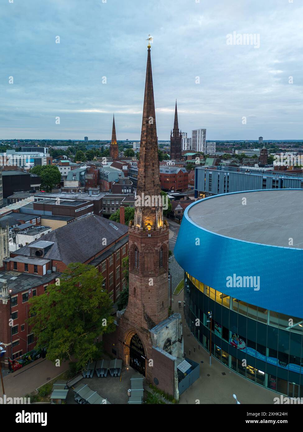 Aus der Vogelperspektive die heilige dreifaltigkeitskirche, die hoch in der städtischen Landschaft von coventry, großbritannien, steht, während die Sonne untergeht Stockfoto