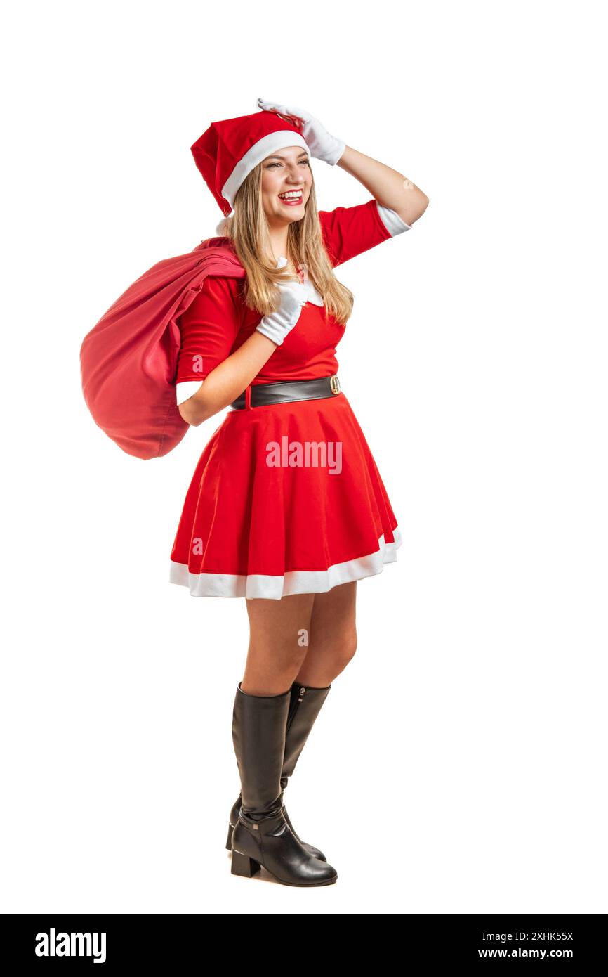 Der junge Weihnachtsmann lächelt mit seinem roten Anzug und einer Geschenktüte auf weißem Hintergrund. Ganzkörper-Studiofoto Stockfoto