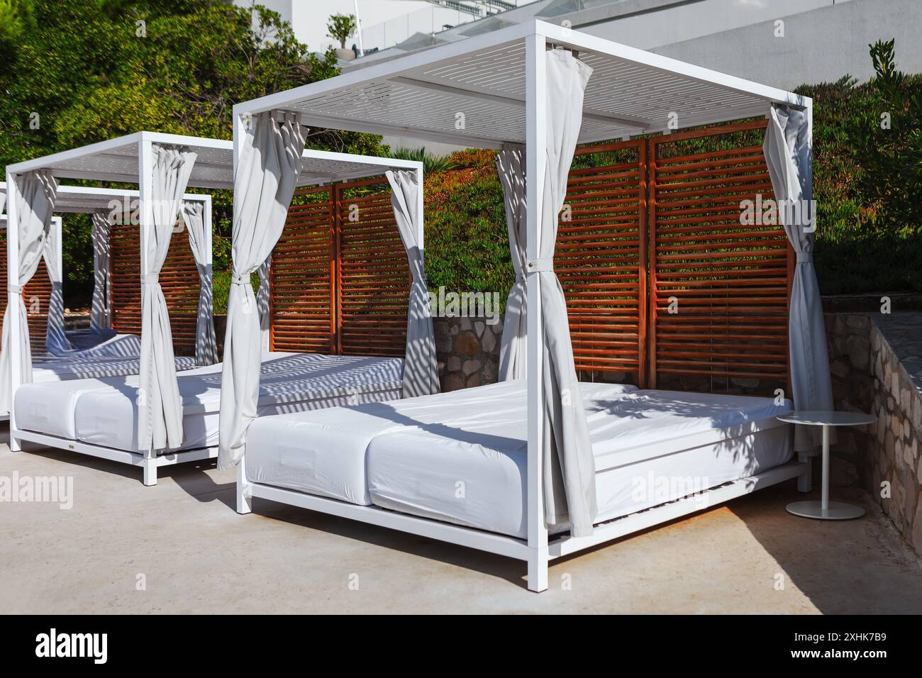 Strandliegen mit Vorhängen sind in einer Reihe angeordnet. Resort Himmelbett zum Entspannen im Freien Stockfoto