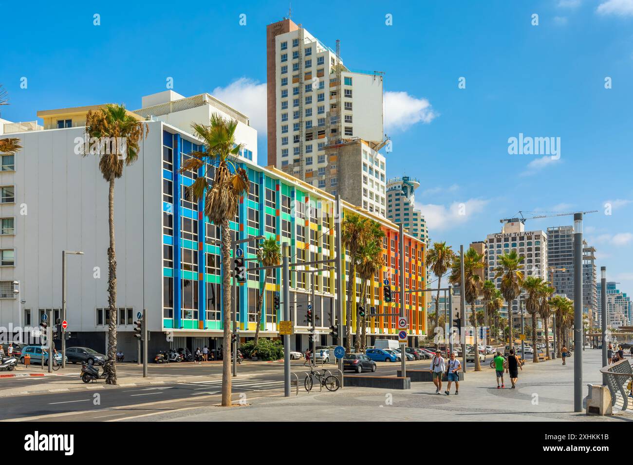 Menschen gehen auf der Promenade mit Palmen vor dem Dan Hotel Gebäude mit Regenbogenfassade in Tel Aviv, Israel. Stockfoto