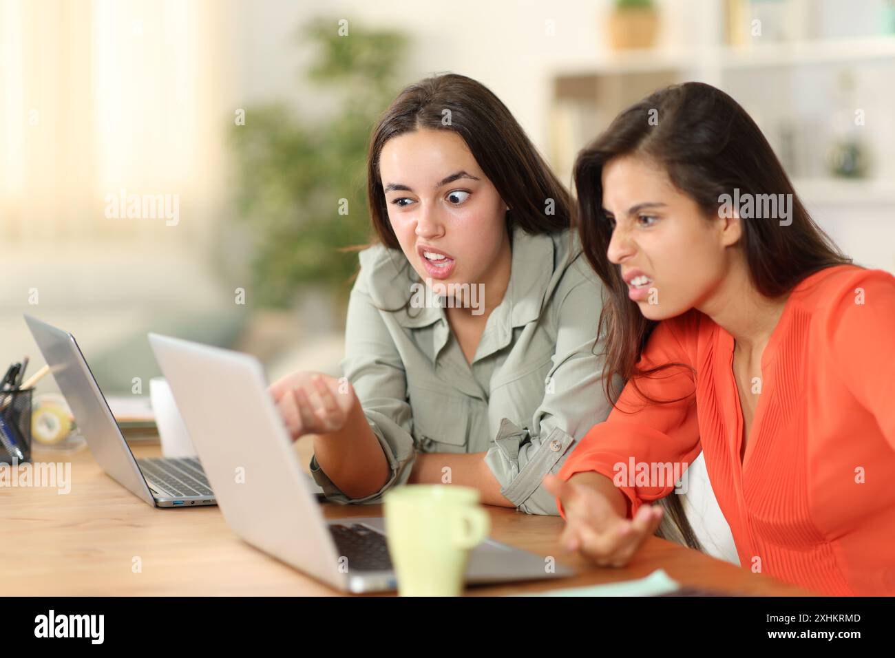 Zwei verärgerte Tele-Mitarbeiter, die zu Hause auf dem Laptop seltsame Inhalte überprüfen Stockfoto