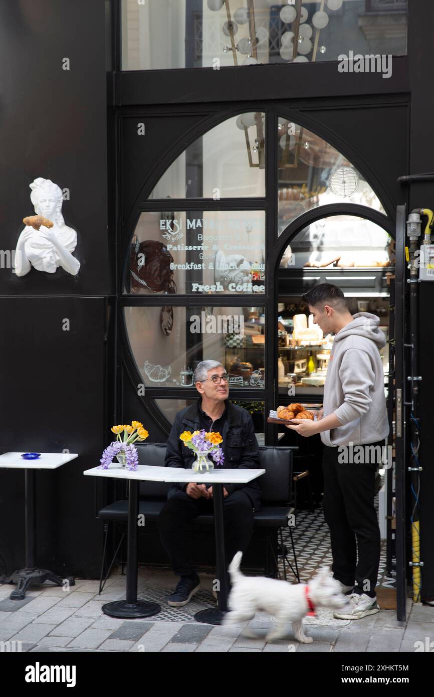 Türkei, Istanbul, westlicher Mann mit Hund auf der Terrasse eines französischen Konditorcafés Stockfoto