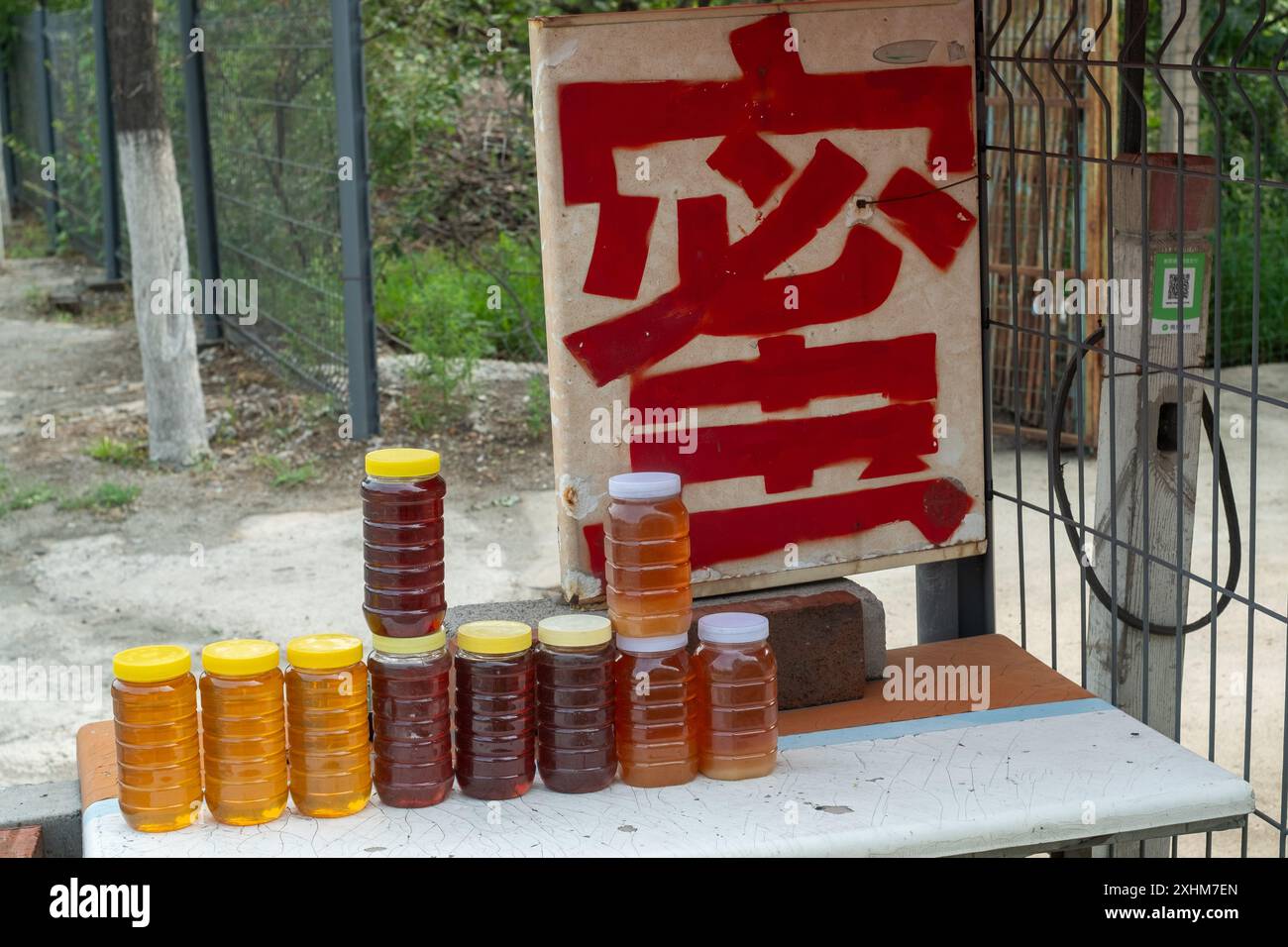 Chinesische Imker verkaufen ihren eigenen frisch zubereiteten Honig am Straßenstand in Huairou, einem Vorort von Peking, China. Chinesisches Zeichen liest sich als Honig. Stockfoto