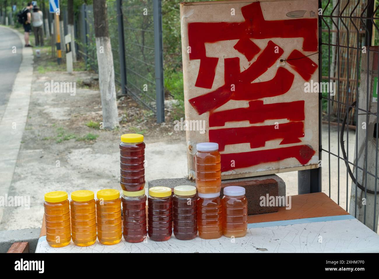 Chinesische Imker verkaufen ihren eigenen frisch zubereiteten Honig am Straßenstand in Huairou, einem Vorort von Peking, China. Chinesisches Zeichen liest sich als Honig. Stockfoto