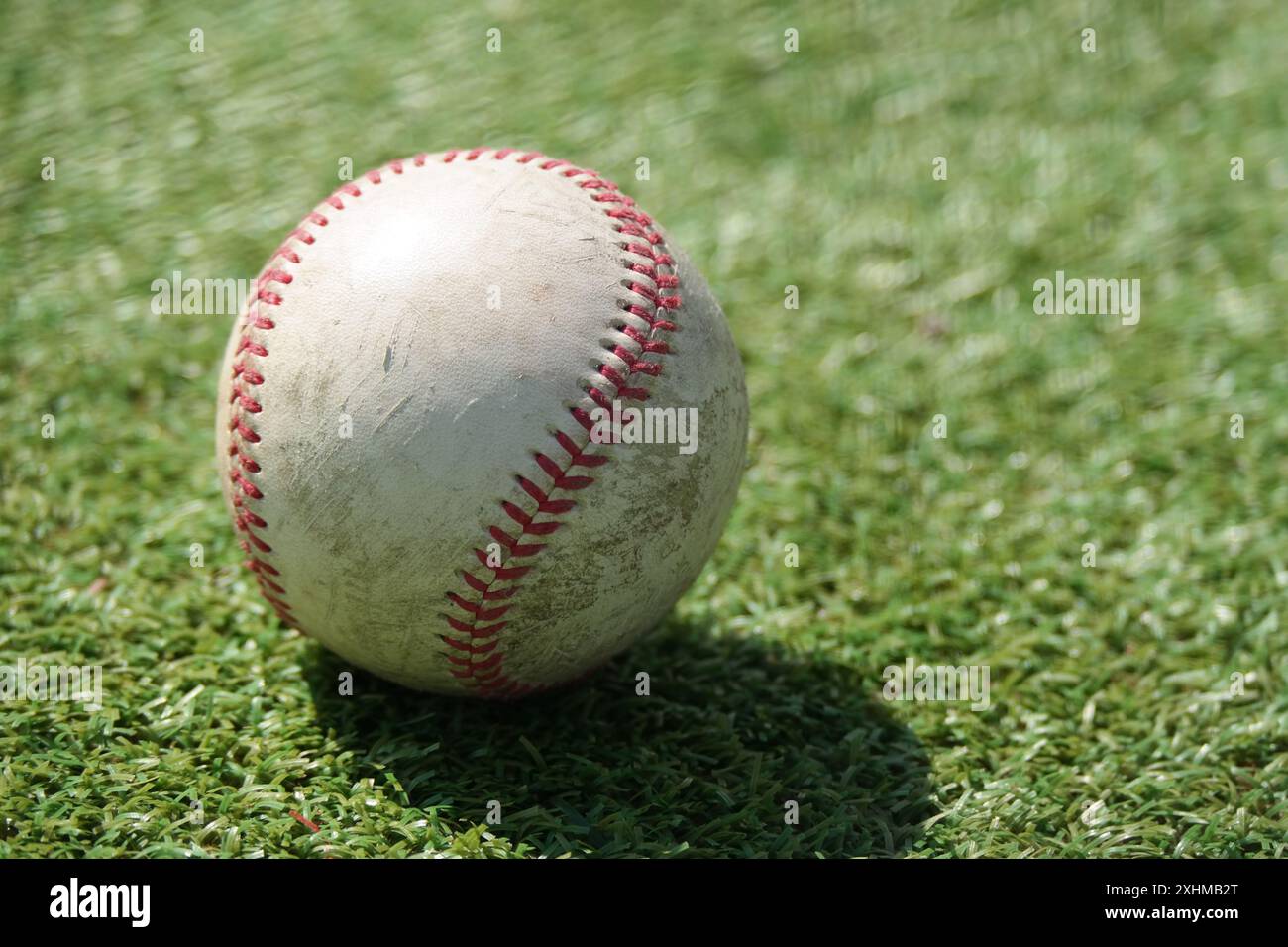 Ein alter Baseball liegt auf dem grünen Grasfeld Stockfoto