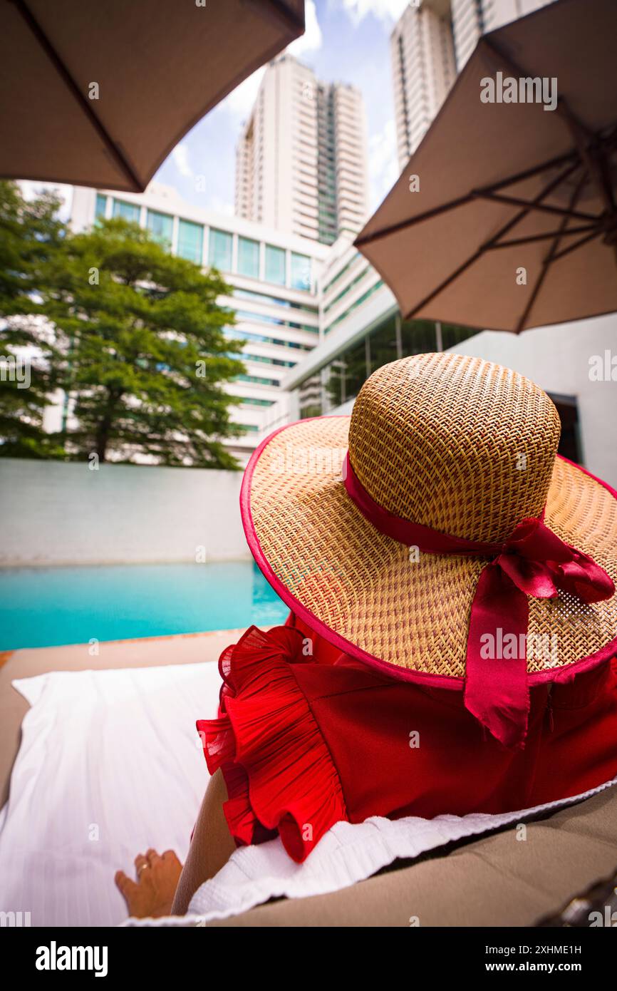Rückansicht einer Frau mit Hut, die sich am Pool des Hotels entspannte Stockfoto