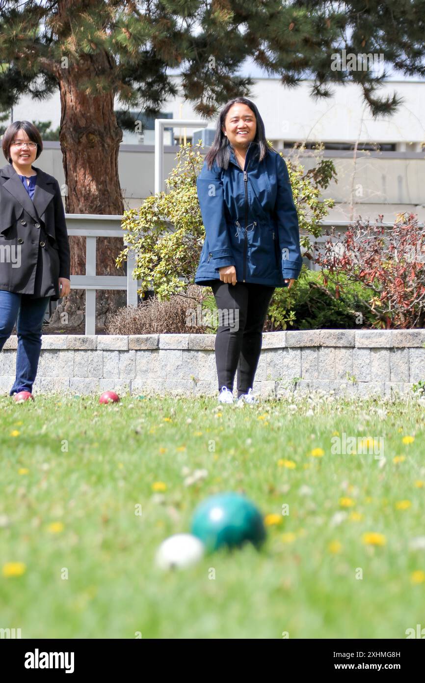 Zwei Frauen spielen Bocce draußen auf einem Rasenfeld Stockfoto