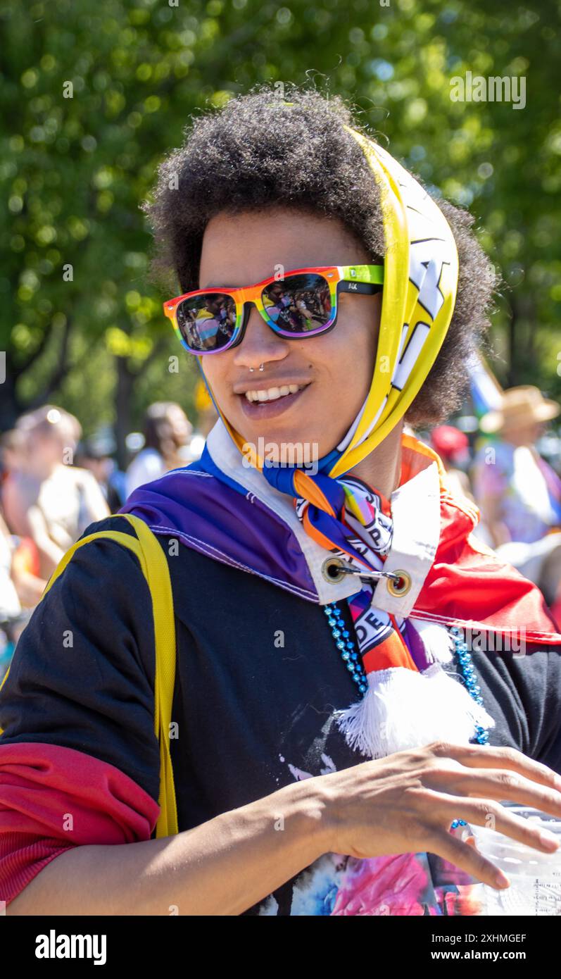 Person bei einer Stolz-Veranstaltung mit Regenbogensonnenbrille und Schal Stockfoto