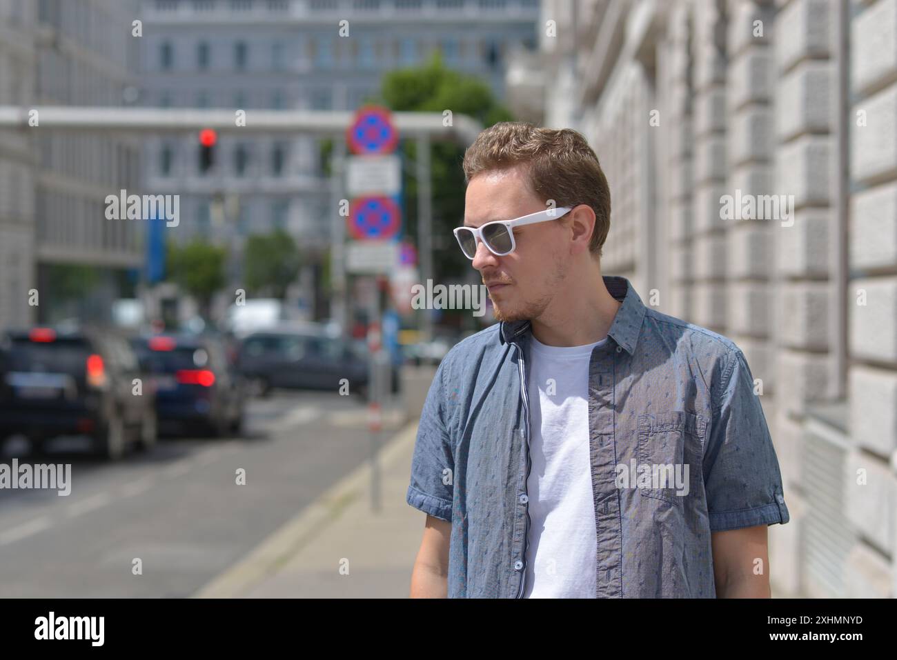 Ein Mann mit Sonnenbrille auf der Straße in Wien. Das Konzept des heißen, sonnigen Wetters in der Stadt. Ein Mann leidet unter der Hitze. Stockfoto
