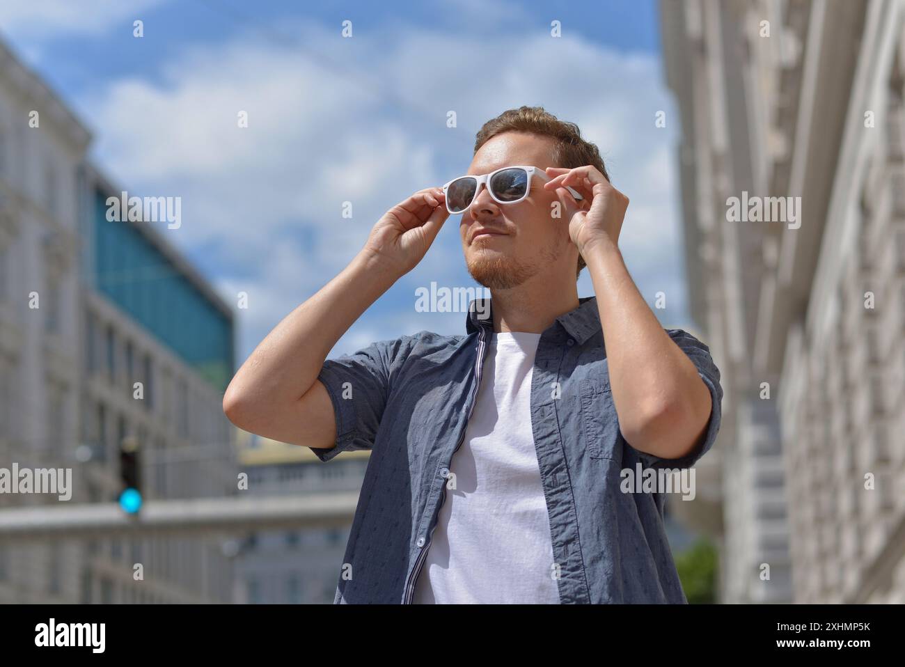 Ein Mann mit Sonnenbrille auf der Straße in Wien. Das Konzept des heißen, sonnigen Wetters in der Stadt. Ein Mann leidet unter der Hitze. Stockfoto