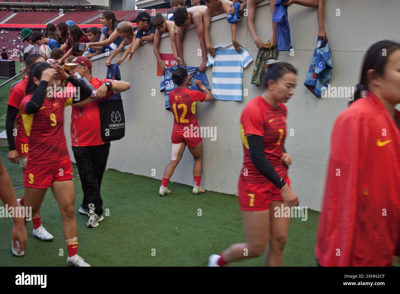 Eine Spielerin der chinesischen Rugby Sevens Nationalmannschaft, die nach einem Spiel während der Madrid Sevens Rugby-Shirts an Kinder signiert. Stockfoto